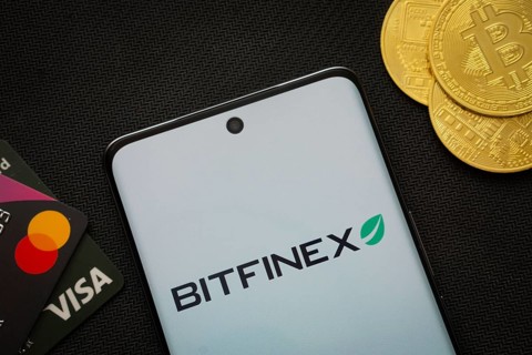 Dhaka, Bangladesh- 15 June 2025: Smartphone displaying Bitfinex logo surrounded by Bitcoin coins