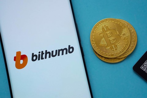 Dhaka, Bangladesh- 07 May 2025: Bithumb logo on smartphone screen near Bitcoin coin and QR code on