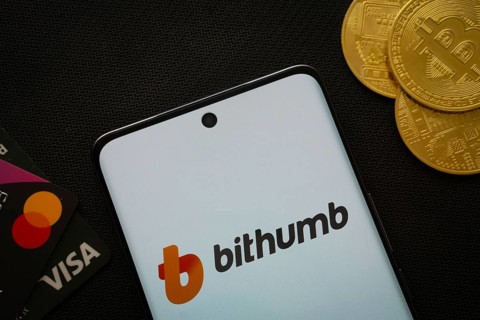 Dhaka, Bangladesh- 07 May 2025: Smartphone displaying Bithumb logo surrounded by Bitcoin coins and