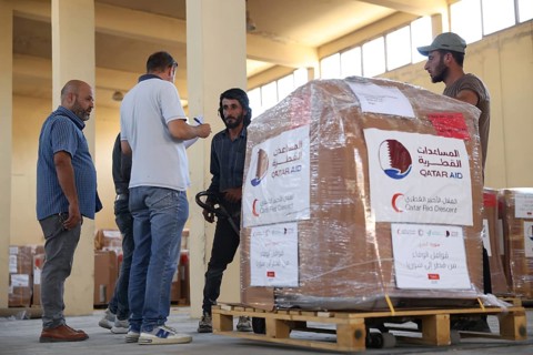 Relief workers unload boxes of medical aid provided by Qatar at Damascus International Airport,