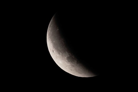 After a total lunar eclipse, the moon appears shortly after its rise in the evening sky as a