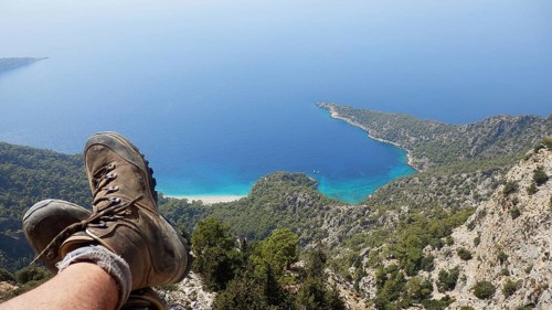 A person relaxes while hiking on a steep cliff in the mountains with spectacular views of hiking