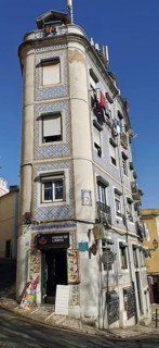 A tall, narrow building on a sloping street with typical facades, Lisbon, Portugal