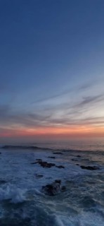 Sunset over a peaceful ocean with rocks in the foreground, hiking the Fisherman's trail, Rota