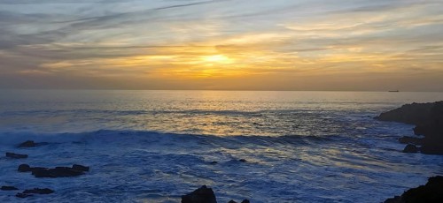 The sun sets over the ocean with visible waves, hiking the Fisherman's Trail, fishing trail, rota