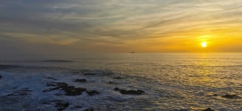 Colourful sunset over the calm sea with a ship on the horizon, hiking the Fisherman's Trail, Rota
