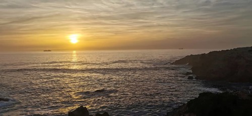 Calm sunset over the sea with two ships on the horizon, hiking the Fisherman's trail, Rota