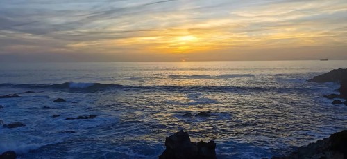 Sunset over a peaceful ocean with rocks in the foreground, hiking the Fisherman's trail, Rota