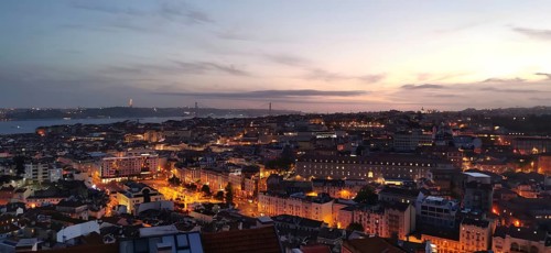 Panoramic view of Lisbon, city view with illuminated streets and buildings under a twilight sky,