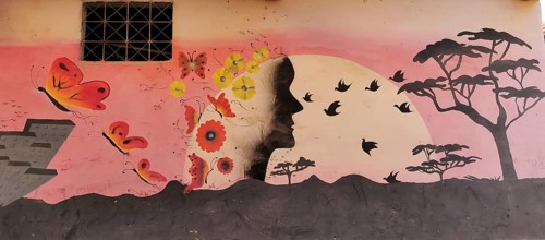 Artful wall painting depicting a human silhouette surrounded by butterflies and flowers,