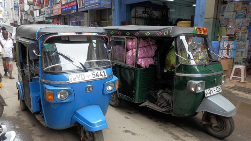 Colourful tuktuks park along a lively city street with shops, Sri Lanka