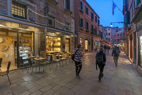 Photographers traveling in the old town of Venice, Veneto, Italy in the evening