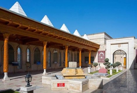 Traditional courtyard with fountain and decorated wooden pillars under clear skies, Istiklal Harbi