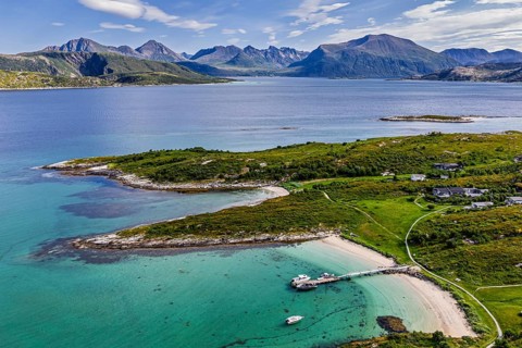 Aerial view over island Sommaroy, sandy beaches, mountain range in the back, Norway