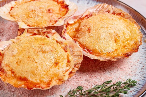 Scallop, baked in shells, with cheese and spices, on a plate, homemade