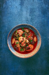 Seafood in tomato sauce with olives, on a dark blue background