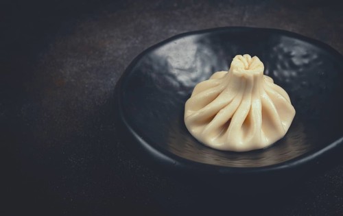 One khinkali, on a black plate, top view, cooking concept, Georgian cuisine