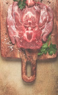 Raw steak, veal neck on the bone, fresh meat, on a cutting board, with spices, top view, without