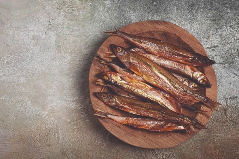 Cold smoked capelin, on a wooden bowl, top view, no people
