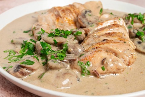 Chicken in cream sauce with mushrooms, on a plate, no people