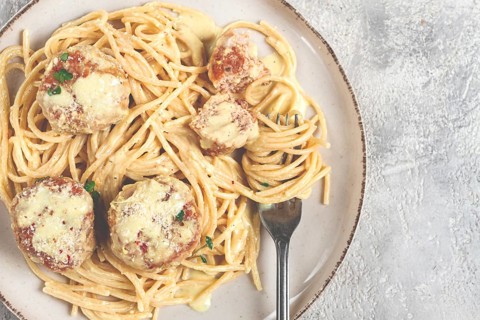 Spaghetti with chicken meatballs, with cream sauce, and parmesan cheese, and decorated with