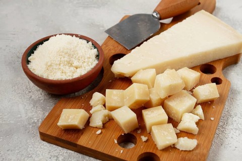 Freshly sliced and grated cheese, parmesan cheese, Gran gusto. Grana padano. on a wooden chopping
