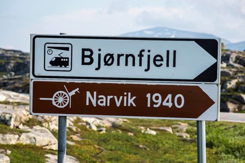 Signpost to Bjørnfjell railway station, railway line Kiruna-Narvik, and world war II memorial,