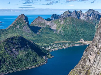 Aerial view from top of Mt. Grytetippen towards village Fjordgard, Mt. Segla and Mt. Hesten, Senja