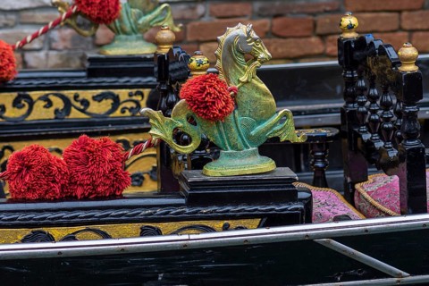 Mythological horse figures and red pompoms decorate the gondola, Venice, Veneto, Italy