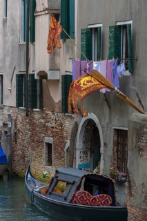Flying flags of the Republic of Venice on a residential building, a gondola on the canal, Venice,