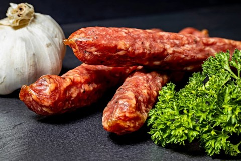 Still life with garlic, salami and parsley on dark background, crunchy pepperbite sausage