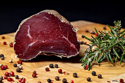 Delicious piece of raw sausage on wooden board decorated with peppercorns, delicacy ham fresh from