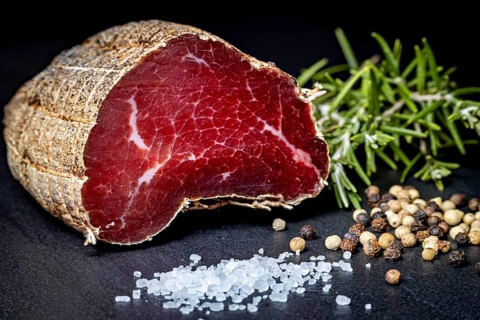 Delicious sausage with salt and pepper on a dark slate plate, delicacy ham fresh from the butcher