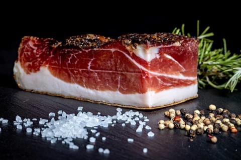 Fat bacon on a dark background with salt and spices, delicacy ham fresh from the butcher