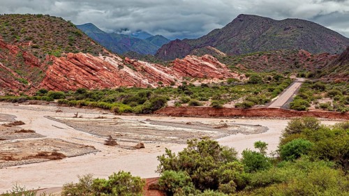 Picturesque valley with road surrounded by red rocks and green vegetation, the landscape and