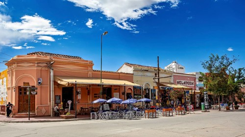 Urban street scene with restaurants and outdoor seating under a clear blue sky, Downtown Cafayate,