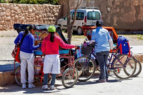 Three woman standing at roadside carts with bicycles, people in the streets of San Antonio de los