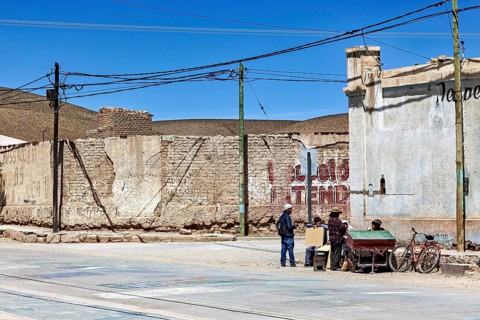 Small group of people talking on a street corner in a dry city with old buildings, San Antonio de