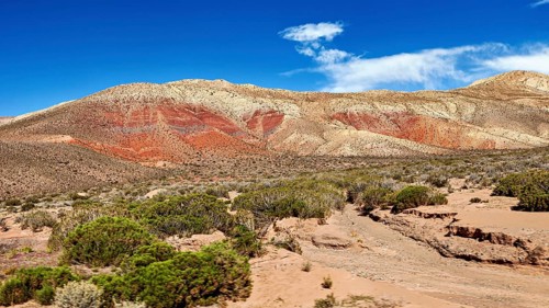 Red-brown hills in a sandy desert landscape under clear blue sky, the landscape and colorful rock
