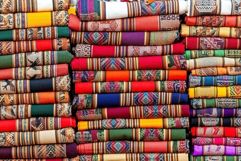 Close-up of stacked, colorful fabrics with traditional patterns, tourist and souvenir market of