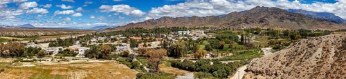Panorama of a green village nestled in hilly and mountainous landscape, roads through the Quebrada