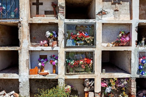 Tomb niches in a weathered wall decorated with flowers and crosses, The Cachi cemetery in Argentina