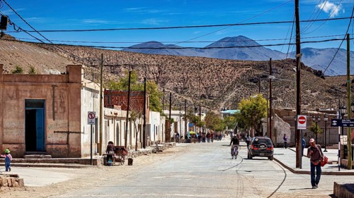 People and vehicles in a small desert town surrounded by rugged hills, San Antonio de los Cobres,