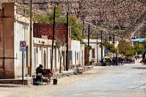 People walk along a picturesque rural road with old buildings and trees, San Antonio de los Cobres,