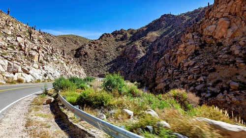 Road winds through rocky gorge in a sunny desert landscape, roads through the Quebrada de Cafayate