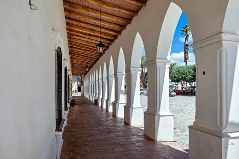 Corridor with arcades and wooden roof, leads outdoors in sunny weather, The arcades of Cachi in