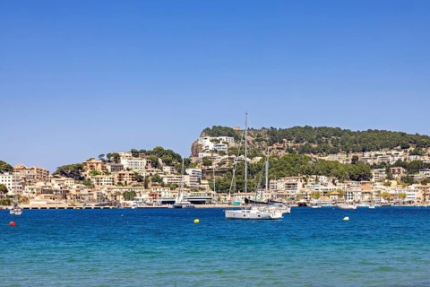 Scenic view of a coastal village with turquoise blue water and anchored sailboats and yachts and a
