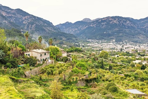 Serene rural landscape featuring a traditional stone house surrounded by vibrant greenery and