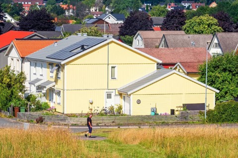 Alone man walking on a walkway in a residential area with wooden houses a sunny summer day,