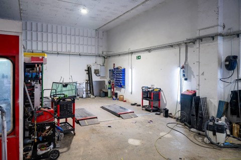 Empty car body shop interior with lifts, paint booth, tools and spare parts on carts and cabinets,
